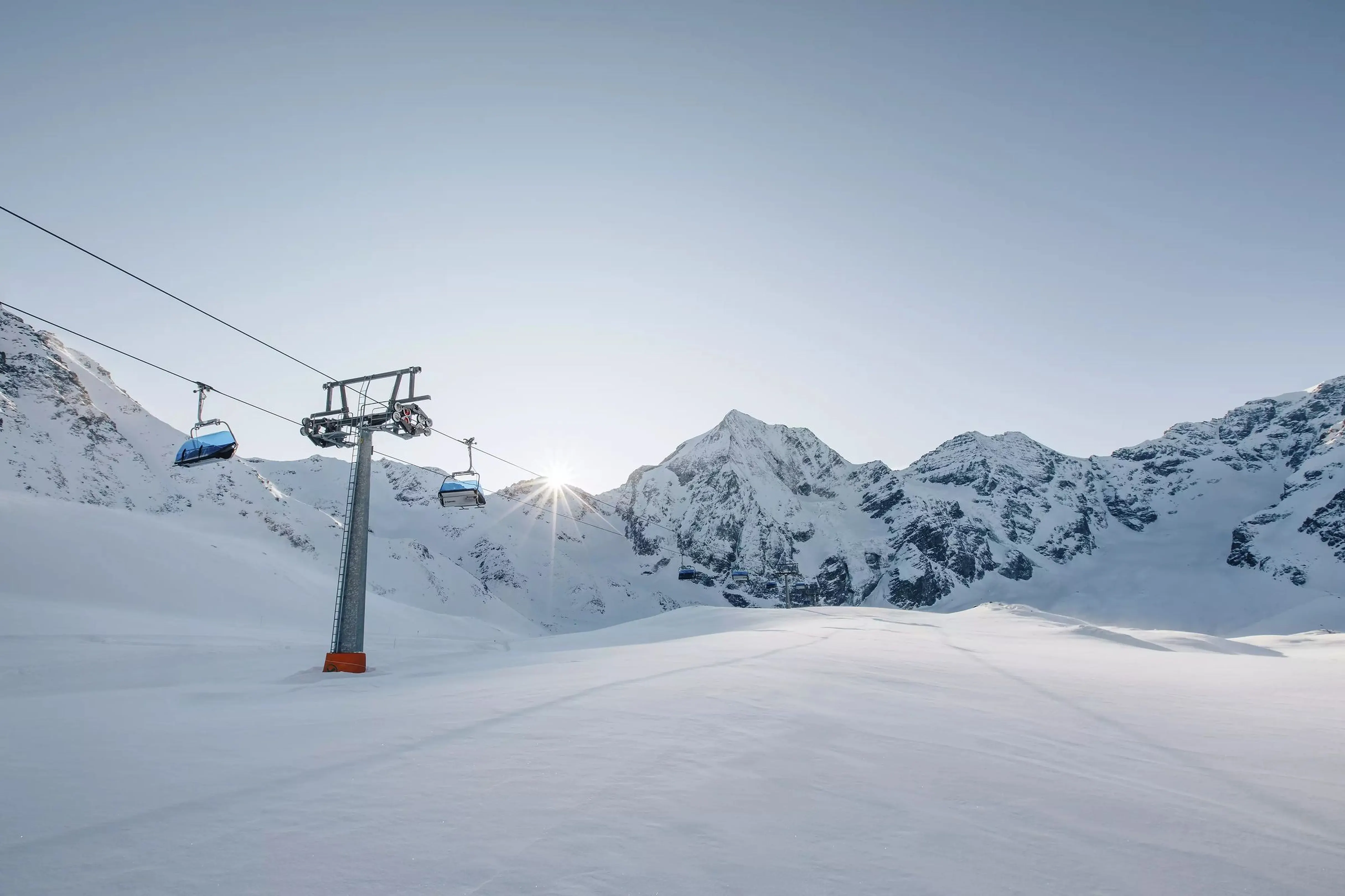 Sessellift im Tiefschnee, die Sonne steht hinter der Königsspitze