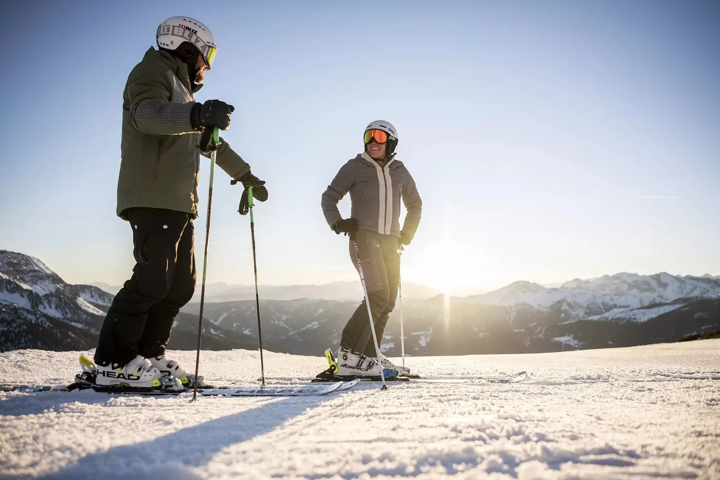Zwei Skifahrer stehen in der Abendsonne auf der Piste