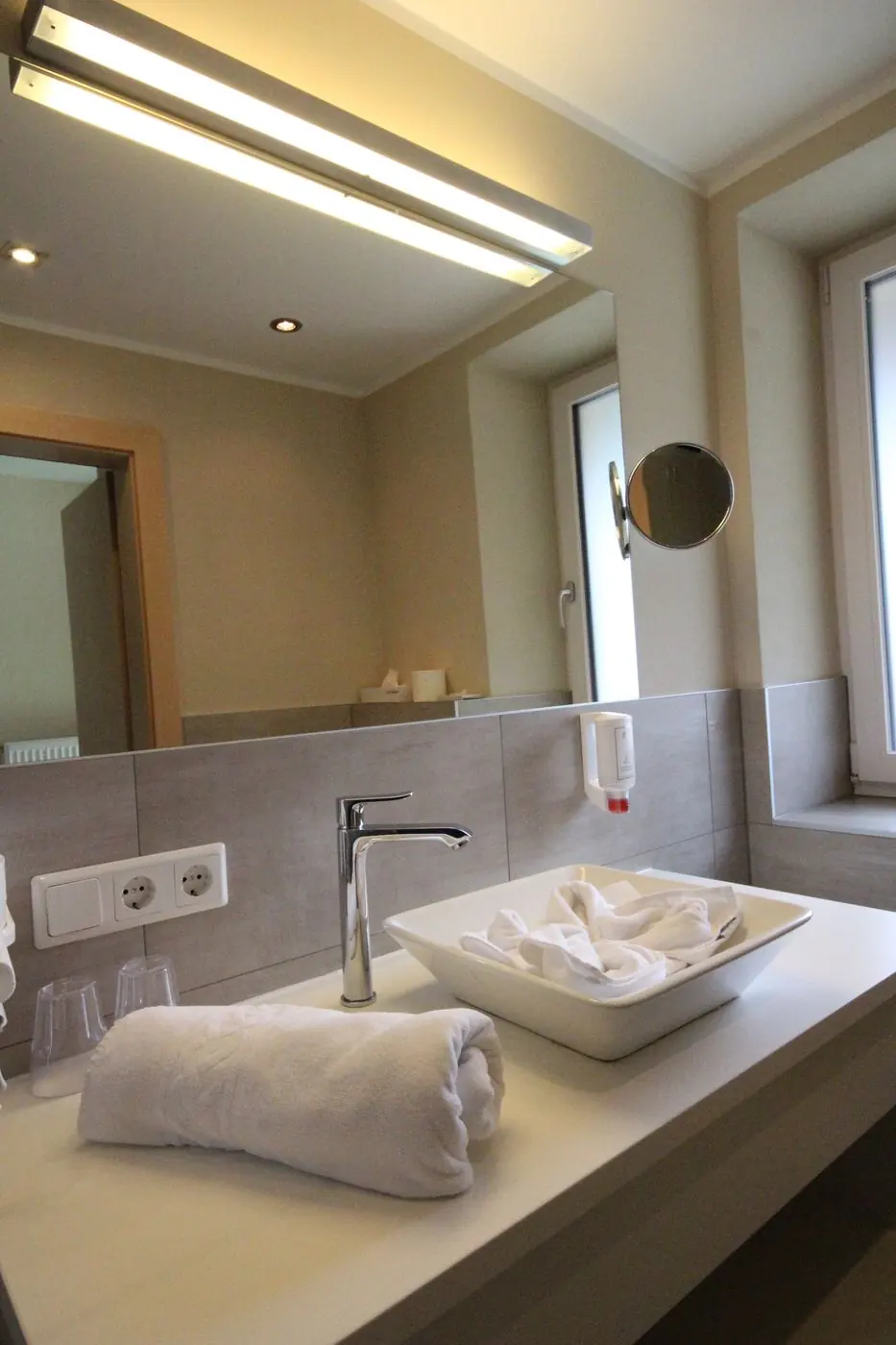 Badezimmer mit Aufsatzwaschbecken und beleuchtetem Spiegel