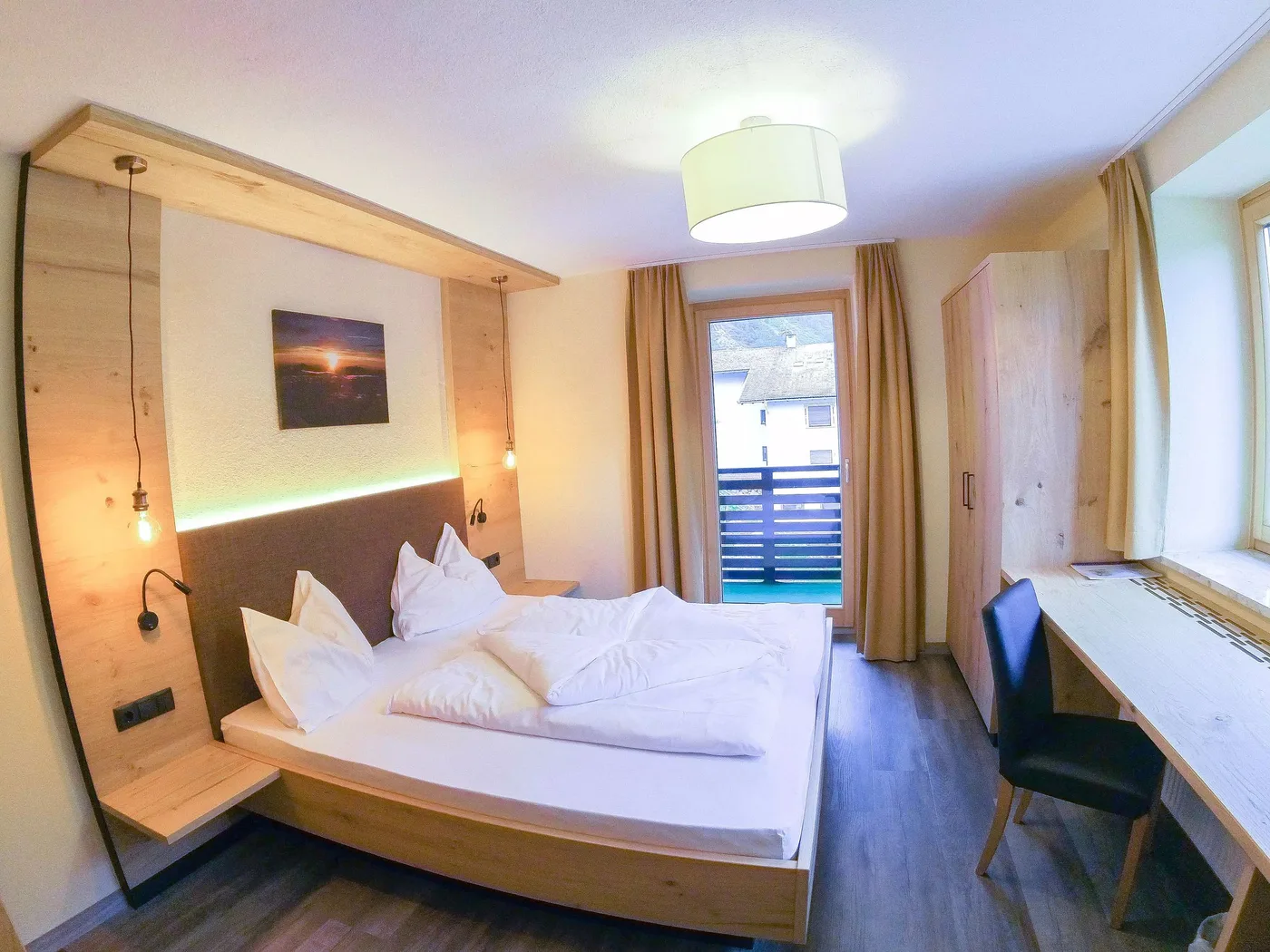 Doppelzimmer mit Holzbett und Balkontür